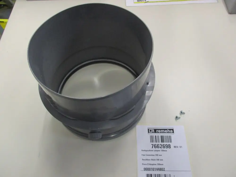 Grauer Adapter von Remeha mit einem Anschlussstück. Im Bild sind auch Schrauben zu sehen. Das Produkt hat eine runde Öffnung und eine flache Unterseite.